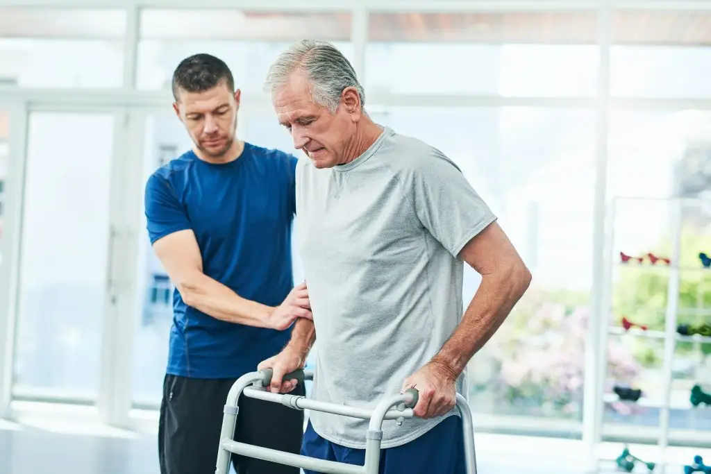 Cropped shot of a young male physiotherapist helping his senior patient to use a walker at the rehabilitation center
