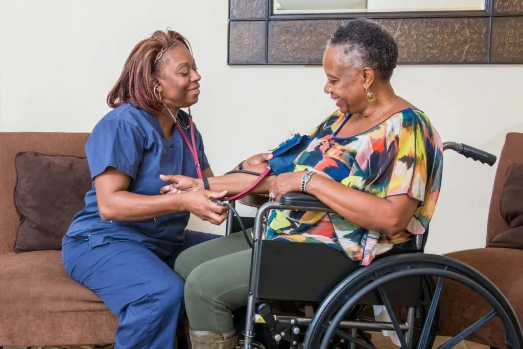 A home healthcare worker is taking the blood pressure of a senior woman in a wheelchair.