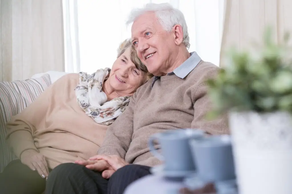 elderly couple close smiling on a couch