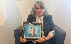 Image of a smiling woman holding a framed image of her senior mother.