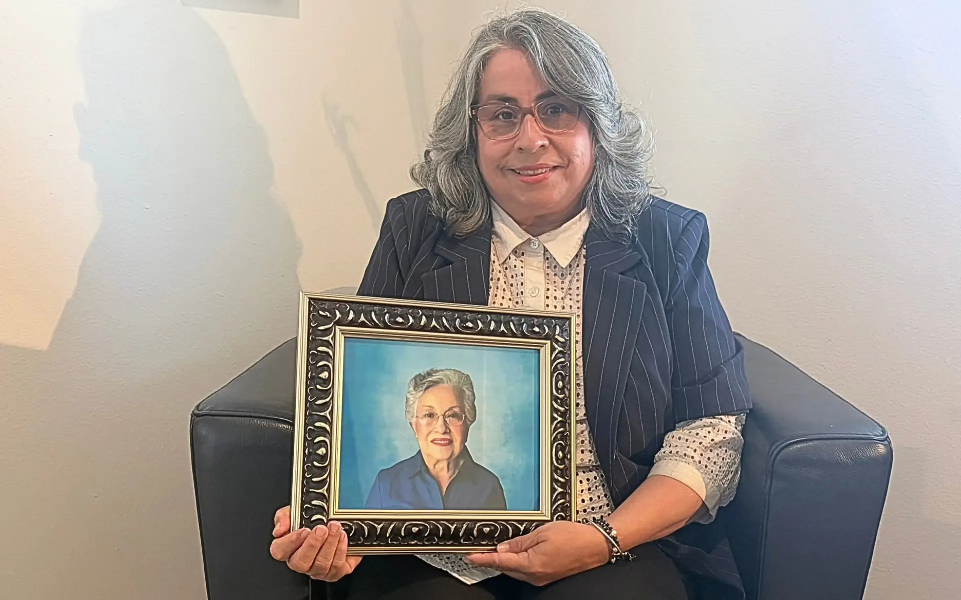 Image of a smiling woman holding a framed image of her senior mother.
